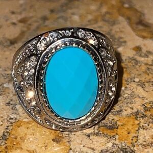 Costume jewelry silver tone ring with turquoise color acrylic center stone.